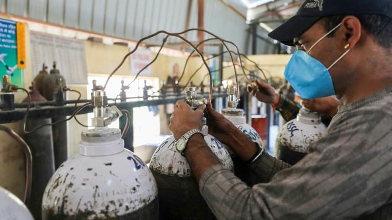 Un employé remplit des bouteilles d'oxygène destinées aux hôpitaux pour les malades du Covid-19, le 23 avril 2021 à Jammu, en Inde