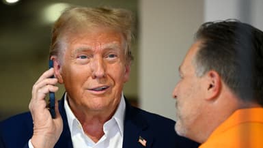 Donald Trump parle au téléphone dans le garage McLaren avant le Grand Prix de F1 de Miami à l'autodrome international de Miami, le 5 mai 2024 à Miami, en Floride.