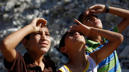 Des enfants palestiniens en train d'observer un avion de l'armée israélienne dans le nord de la bande de Gaza, le 4 août