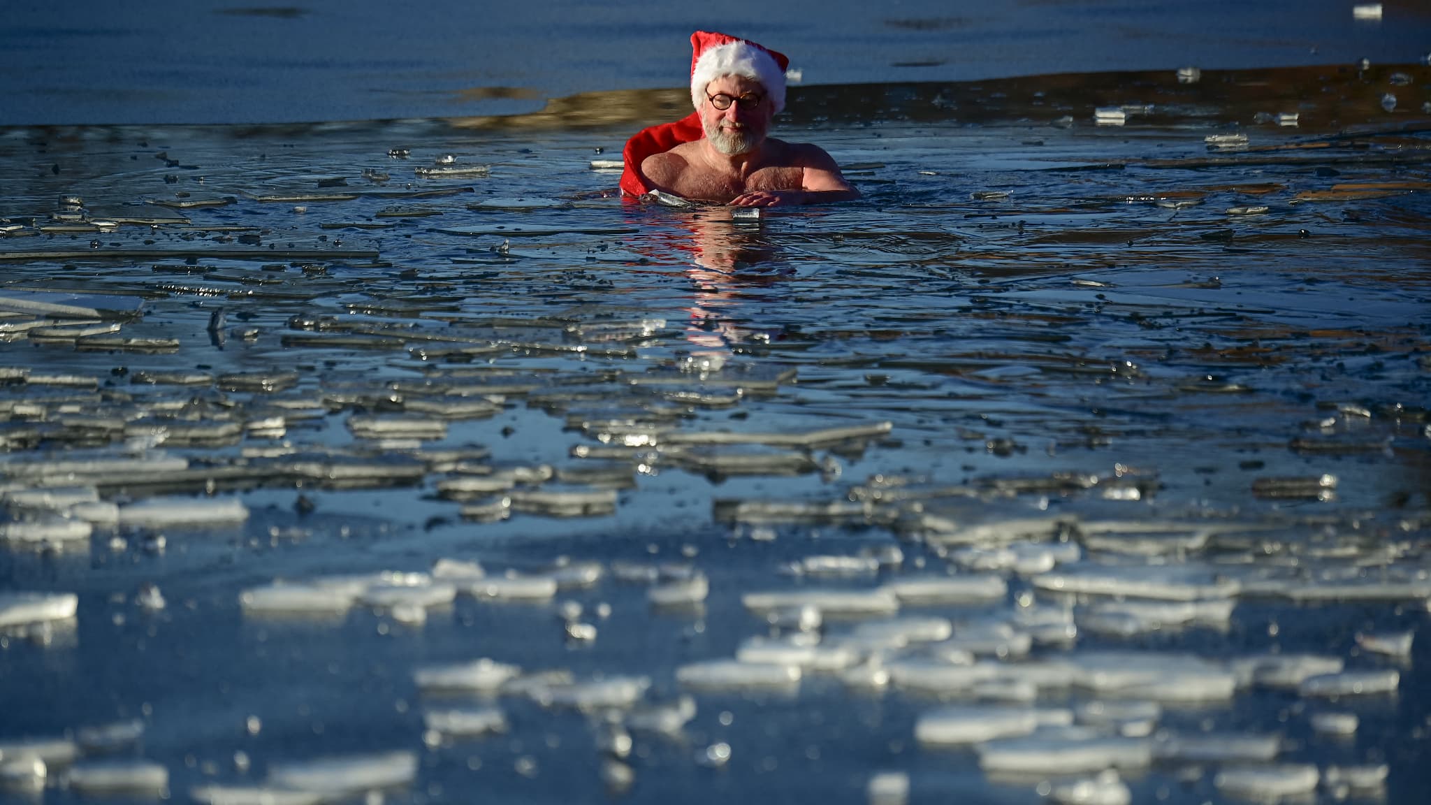 Un membre du club de natation Berliner Seehunde (les phoques de Berlin) prend le traditionnel bain de Noël au lac Orankesee lors d'une journée ensoleillée le 25 décembre 2021 à Berlin.
