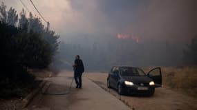 Un habitant arrosant les alentours de sa maison à Dion, en Grèce, ce lundi 12 août 2024.