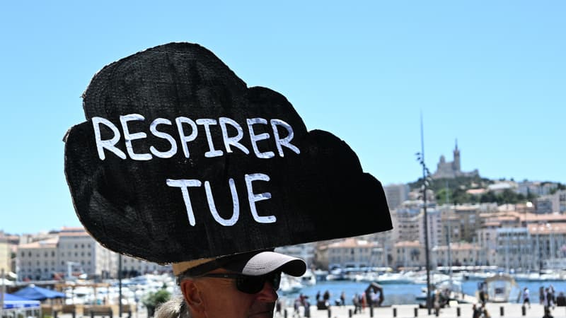 Un manifestant avec une pancarte "Respirer tue" lors d'une manifestation contre la pollution de l'air à Marseille, le 11 juin 2022.