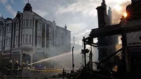 Pompiers à l'oeuvre dans une rue de Tottenham, dimanche matin. Londres se préparait dimanche à une reprise possible des violences dans ce quartier du nord de la capitale après des émeutes sans précédent depuis des années, que les milieux politiques et la
