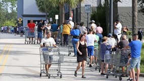 Des client marchent pour rejoindre une file d'attente s'étendant au-delà du parking à l'extérieur d'un entrepôt de vente au détail, alors que les gens se préparent à l'ouragan Ian, à Kissimmee, en Floride, le 25 septembre 2022.