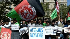 Des manifestants brandissent des drapeaux afghans lors de la manifestation à Paris, le 22 août 2021, pour réclamer l'évacuation des familles afghanes menacées par les talibans