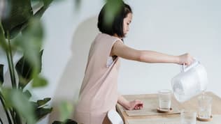 Une jeune fille versant de l'eau avec une carafe filtrante (photo d'illustration).