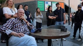 Des personnes se sont rassemblées autour d'une radio portable dans une rue du centre-ville de Madrid pour écouter le discours du Premier ministre espagnol, l'accès à Internet et aux réseaux de télévision étant interrompu en raison d'une panne de courant massive survenue en Espagne le 28 avril 2025.