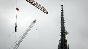 Une grue soulève une statue de Saint-Thomas qui sera replacée au sommet de la flèche de la cathédrale Notre-Dame de Paris, le 24 juillet 2025.