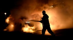 Un pompier éteint une voiture incendiée lors des émeutes qui secouent la capitale suédoise.
