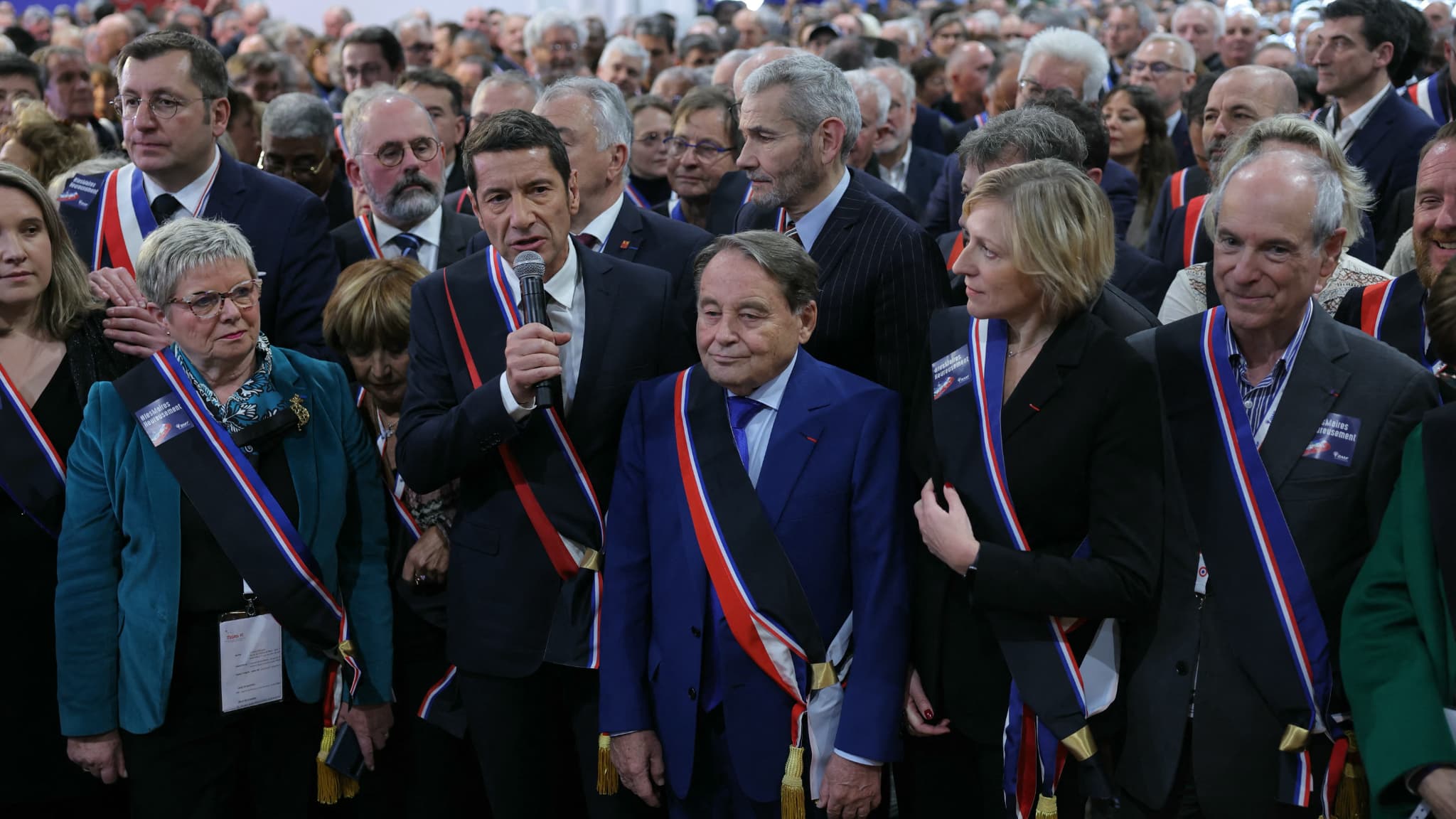 Plusieurs maires dont le président de l'AMF (Association des maires de France) David Lisnard arborant une écharpe tricolore et noire, le 19 juin 2024 à Paris.