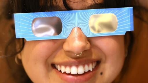 Karolyna Landin, employée de Warby Parker, pose avec une paire de lunettes de protection spéciales éclipse dans la boutique où elle travaille le 11 août 2017 à New York