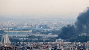 Des volutes de fumée s'échappent d'un site situé près de la tour Azadi (à gauche), dans le centre de Téhéran, alors que les combats entre Israël et l'Iran se poursuivent, le 16 juin 2025. 