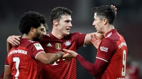 L'attaquant polonais du Bayern Munich, Robert Lewandowski, est félicité par le défenseur français Benjamin Pavard et le milieu de terrain Serge Gnabry, après avoir marqué le 4e but sur le terrain de Stuggart, lors de la 16e journée de Bunesliga, le 14 décembre 2021