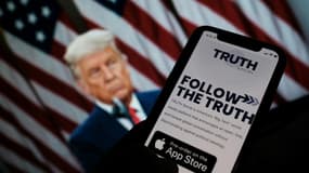 Une personne montre l'application "Truth social" sur son téléphone, devant un fond d'écran de Donald Trump, à Los Angeles le 20 octobre 2021