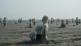 Vue en date du 28 mars 2016 de sculptures de personnes à moitié enterrées dans le volcan de boue qui a surgi de terre le 29 mai 2006 à Sidoarjo