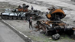 Des habitants regardent un char russe détruit à la périphérie du village de Buzova, à l'ouest de Kiev, le 10 avril 2020.
