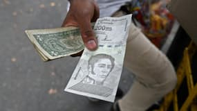 Un billet de 200.000 bolivars à côté de billets de 1 dollar américain dans une rue de Caracas, le 14 avril 2021 au Venezuela