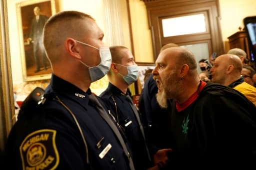 Un manifestant anti-confinement crie sur des policiers au siège du Parlement du Michigan, à Lansing, le 30 avril 2020 Un manifestant anti-confinement crie sur des policiers au siège du Parlement du Michigan, à Lansing, le 30 avril 2020