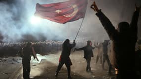 Un manifestant brandit un drapeau turc devant la police anti-émeute lors d'un rassemblement de soutien au maire arrêté d'Istanbul (Turquie), le 24 mars 2025.