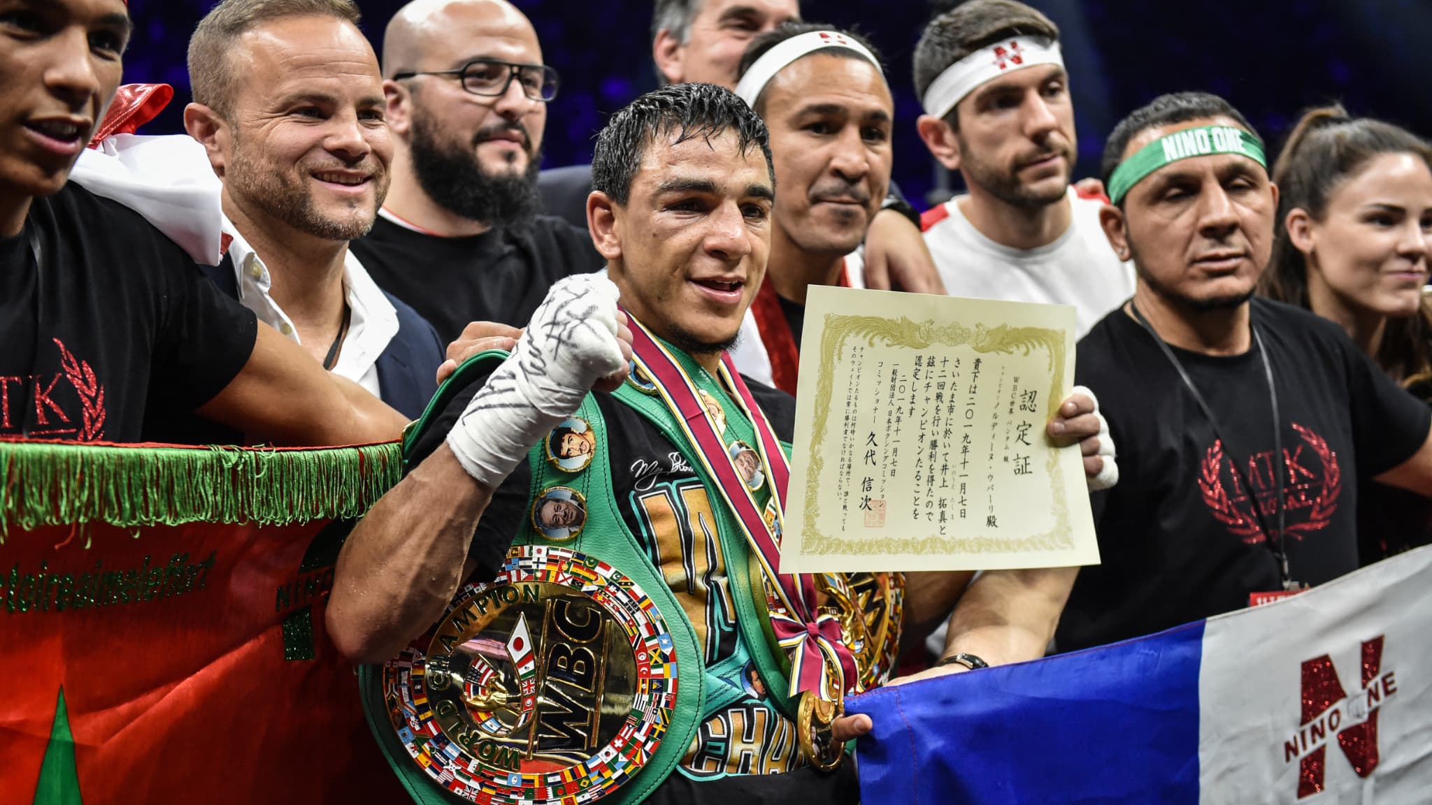 Nordine Oubaali (au centre) avec son équipe et sa ceinture de champion du monde WBC des coqs