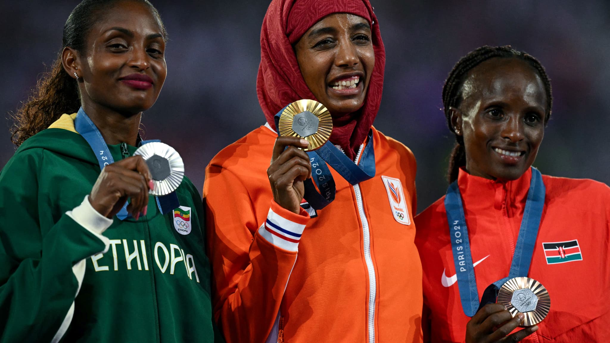 La championne olympique du marathon Sifan Hassan et les médaillée d'argent et de bronze, Tigst Assefa et Hellen Obiri, honorée avec la remise des médailles lors de la cérémonie d'ouverture des JO de Paris 2024, 11 août 2024