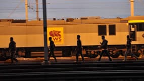 Des migrants longeant les rails du site Eurotunnel près de Calais
