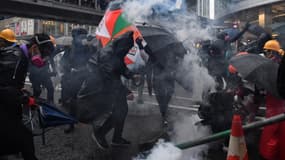 Des manifestants s'abritent du gaz lacrymogène à Hong-Kong, le 25 août 2019. 