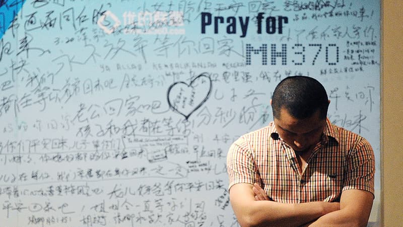 Un homme devant un tableau de soutien aux victimes du vol MH370 à Pékin, le 23 avril 2014.