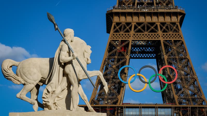 Les anneaux olympiques visibles sur la Tour Eiffel près de la statue restaurée du "Cavalier Arabe" sur le Pont d'Iena à Paris le 4 juillet 2024.