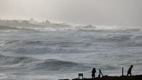 Un piéton marche sur le bord de mer à La pointe de la Torche alors que la tempête Darragh et ses vents violents balayent la côte à Plomeur, dans l'ouest de la France, le 7 décembre 2024.