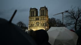 Des passants réunis sous la pluie en dehors du périmètre de sécurité devant la cathédrale Notre-Dame de Paris, le 7 décembre 2024