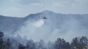 Un hélicoptère éteint un incendie dans le village de Neochori, dans la région de Gortynia, dans le Péloponnèse, en Grèce, le 12 août 2021.