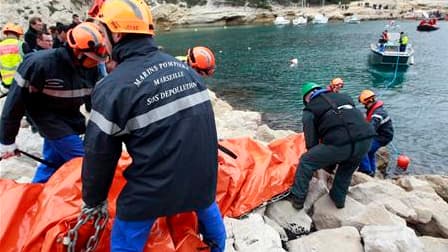 Casque sur la tête, tenue imperméable, les marins-pompiers de Marseille installent un long barrage de plastique souple de couleur orange sur les eaux cristallines de la calanque de Morgiou. Cet exercice contre la pollution maritime est réalisé chaque anné