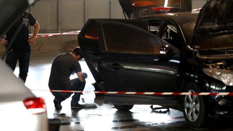 Un officier de la police scientifique examine une voiture abandonnée par Redoine Faïd et ses complices au centre commercial O'Parinor à AUlnay-sous-Bois, le 1er juillet 2018.
