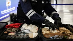 Un douanier inspecte les bagages de passagers à l'aéroport de Roissy-Charles-de-Gaulle, au nord de Paris, le 21 mars 2025
