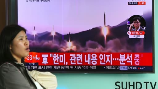 Une femme passe devant un écran de télévision le 22 mars 2017 à Séoul montrant des images d'archives du lancement de quatre missiles nord-coréens