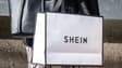Une femme tient un stand de sacs Shein devant le premier showroom permanent du géant chinois de la mode rapide en ligne Shein le jour de l'ouverture de la boutique à Tokyo, le 13 novembre 2022.