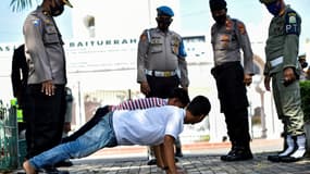 Des passants font des pompes devant des policiers en Indonésie.