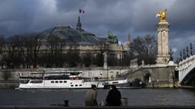 Des personnes assises le long de la Seine devant le Grand Palais, à Paris, le 11 janvier 2023.