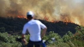 Un passant regarde un feu de forêt à Gignac (Hérault), le 26 juillet 2022.