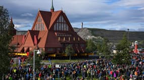 Des personnes se rassemblent pour assister au déplacement de l'église en bois de Kiruna, en Suède, le 19 août 2025.