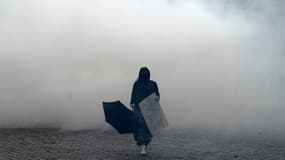 Une manifestante marche devant des gazs lacrymogènes à Place d'Italie, à Paris, le 16 novembre 2019