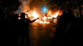 Des policiers se tiennent à côte d'une voiture qui brûle lors de violences à Nanterre, à l'ouest de Paris, le 28 juin 2023