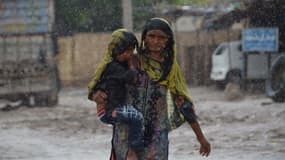 Une femme porte un enfant pendant les pluies et les inondation à Dera Allah Yar, dans la province du Balouchistan, au Pakistan, le 30 août 2022.