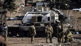 Des militaires ukrainiens devant un blindé russe endommagé à Trostianets, dans le nord-est de l'Ukraine, le 29 mars 2022