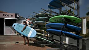 Un jeune surfer devant une école de surf, le 18 juillet 2023.