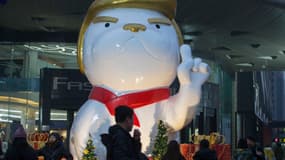 Des passants marchent devant une statue ressemblant à Donald Trump, dans un centre commercial de Taiyuan, en Chine, le 29 décembre 2017. 
