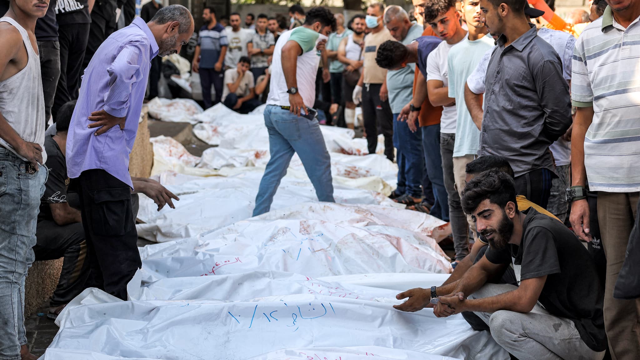 Des personnes se tiennent près des corps des victimes des frappes aériennes israéliennes à l'extérieur de la morgue de l'hôpital al-Shifa dans la ville de Gaza, le 12 octobre 2023.