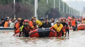 Des équipes de secours évacuent des habitants dans une rue inondée de Zhengzhou, le 22 juillet 2021 en Chine