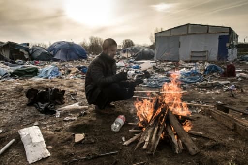 Hemn, un migrant kurde, se réchauffe près d'un feu, le 18 janvier 2016 dans le camp de la "Jungle", à Calais, dans le nord de la France
